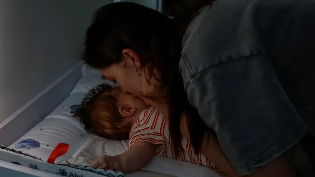 Maryna Tkalich, a Ukrainian mother, kisses her two-month-old baby during a power outage in June